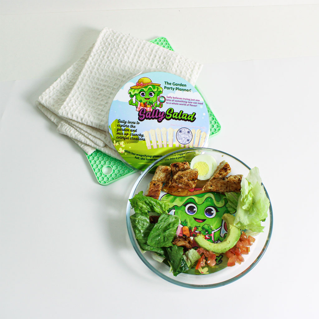 Sally Salad mat peeking through a clear plate filled with salad